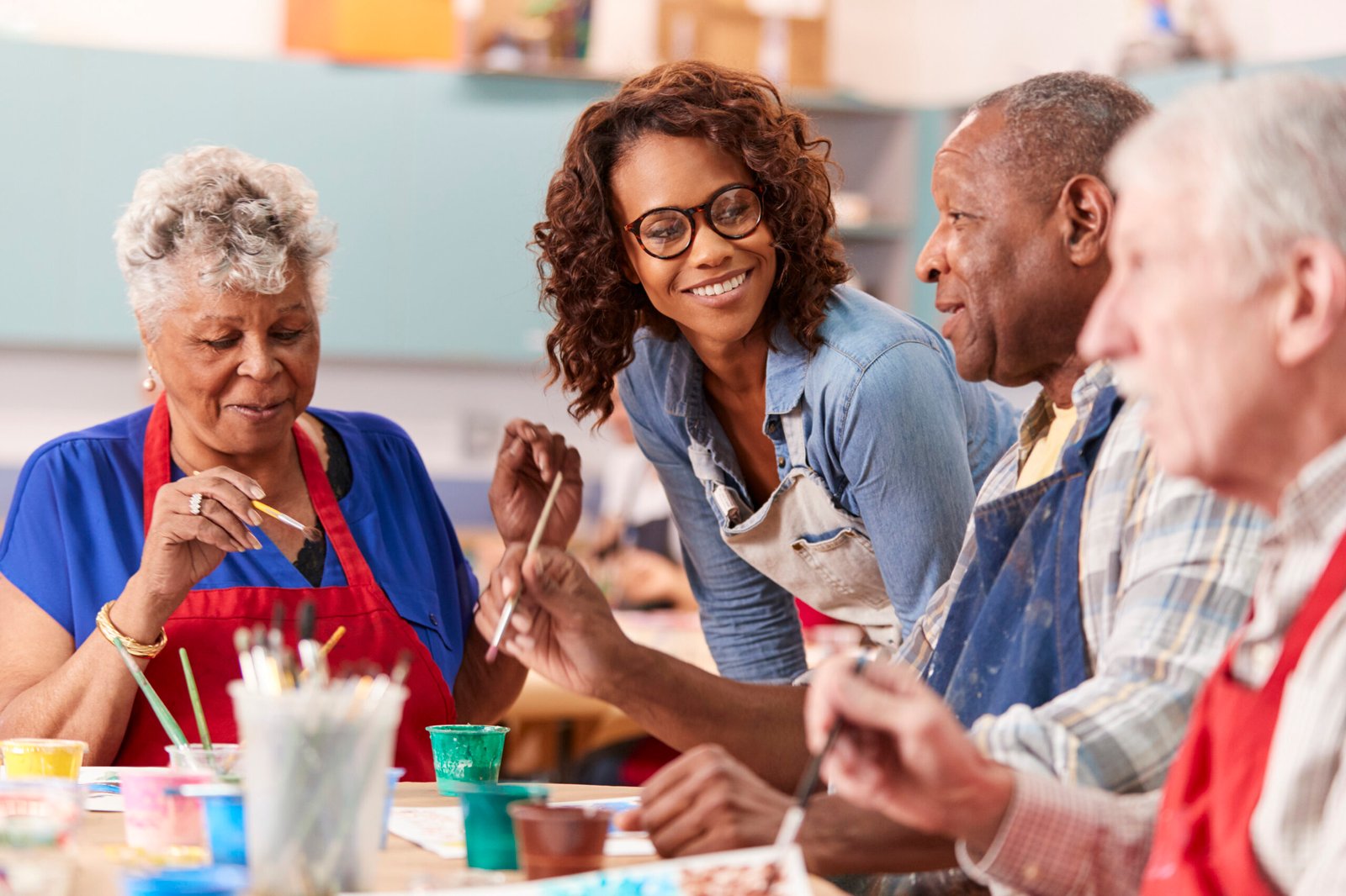 Group Of Retired Seniors Attending Art Class In Community Centre With Teacher